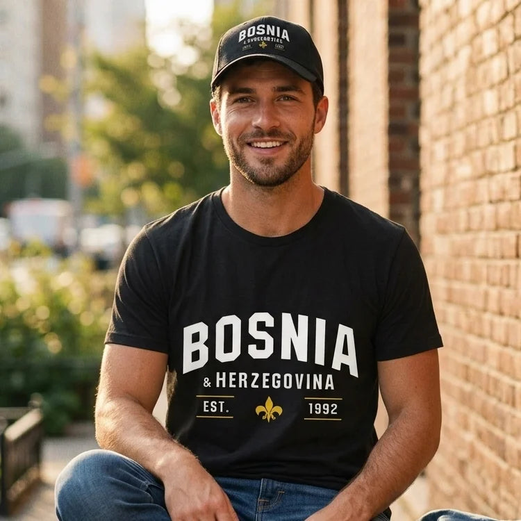 Man wearing a black t-shirt and cap with 'Bosnia & Herzegovina' text, sitting outdoors.