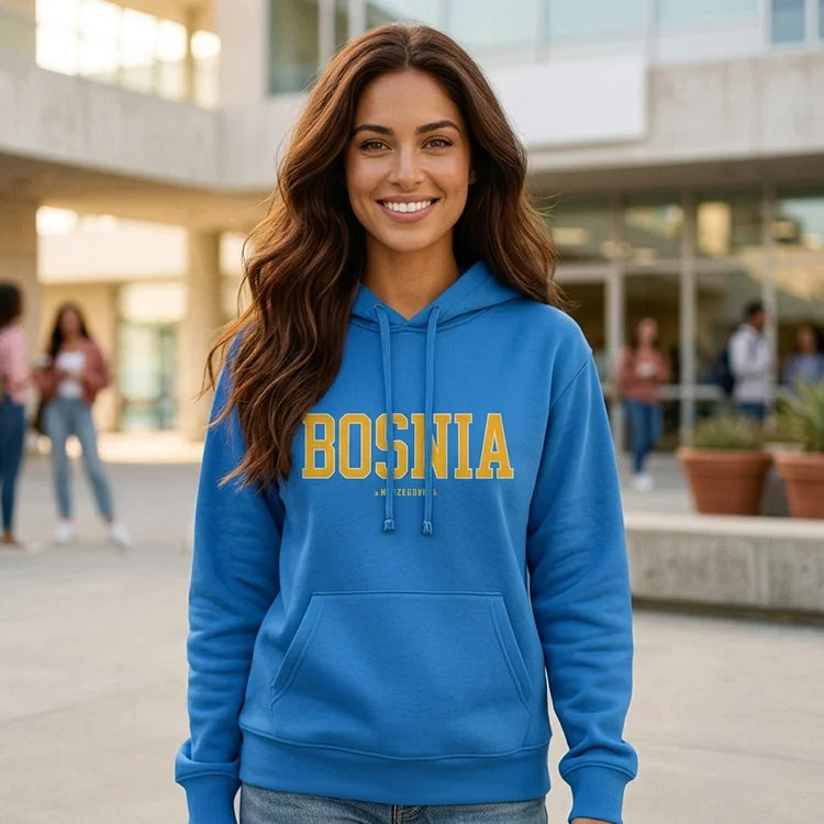 Woman wearing a blue hoodie with 'BOSNIA' printed on it, standing in an outdoor setting.