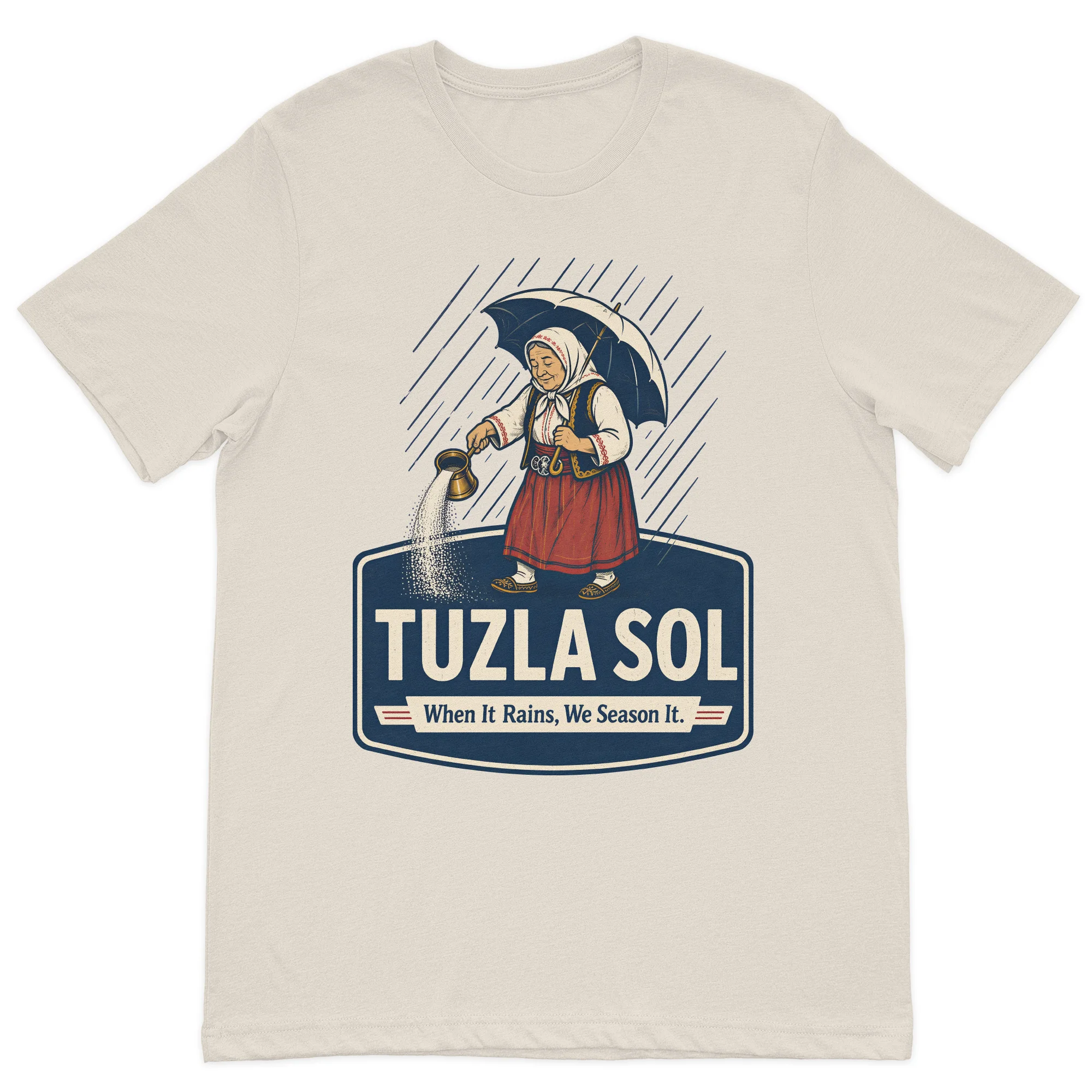 Tuzla Sol graphic t-shirt featuring a traditional Bosnian woman spreading salt in the rain with the slogan "When It Rains, We Season It" on a premium sand cotton t-shirt.
