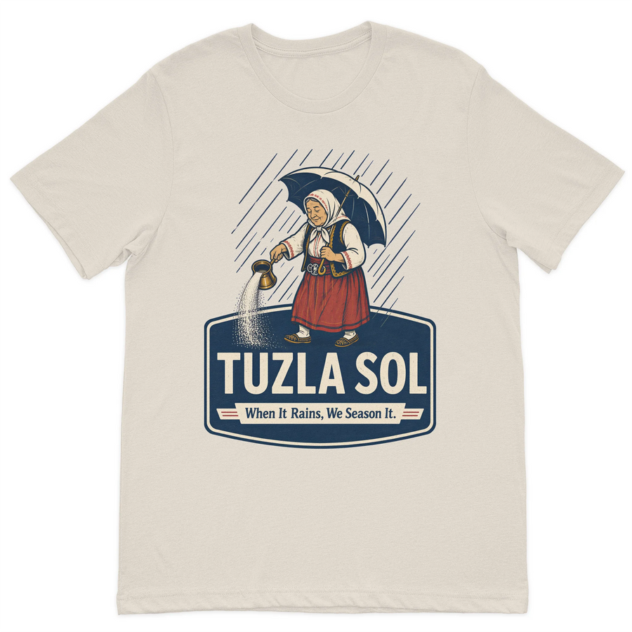 Tuzla Sol graphic t-shirt featuring a traditional Bosnian woman spreading salt in the rain with the slogan "When It Rains, We Season It" on a premium sand cotton t-shirt.